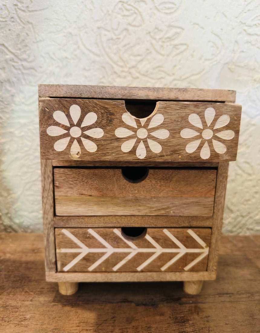 Wooden jewelry box with floral and arrow designs on a textured surface