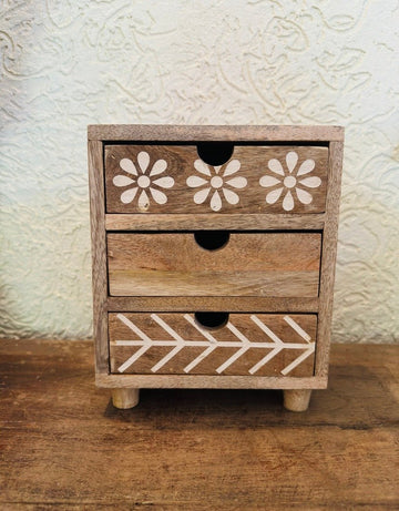 Wooden drawer with floral and geometric patterns on a textured wall background