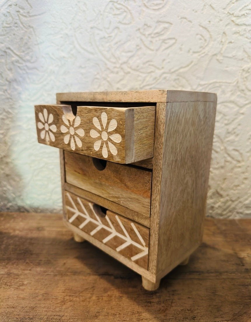 Wooden drawer unit with floral patterns on a textured surface