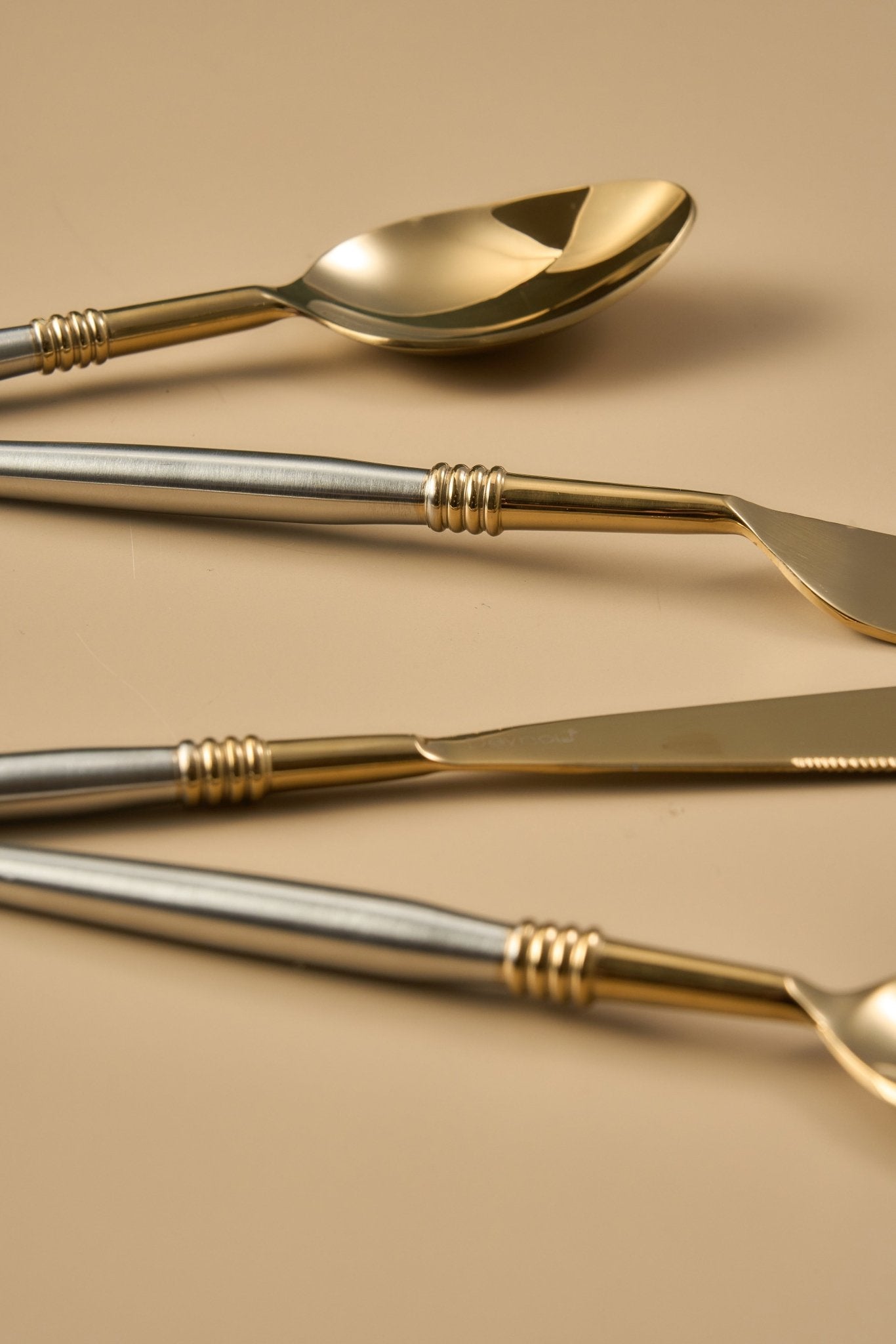 Set of gold and silver cutlery on a beige background