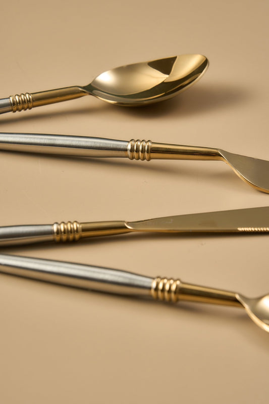 Set of gold and silver cutlery on a beige background