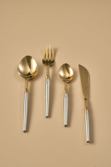 Set of gold and silver cutlery on a beige background