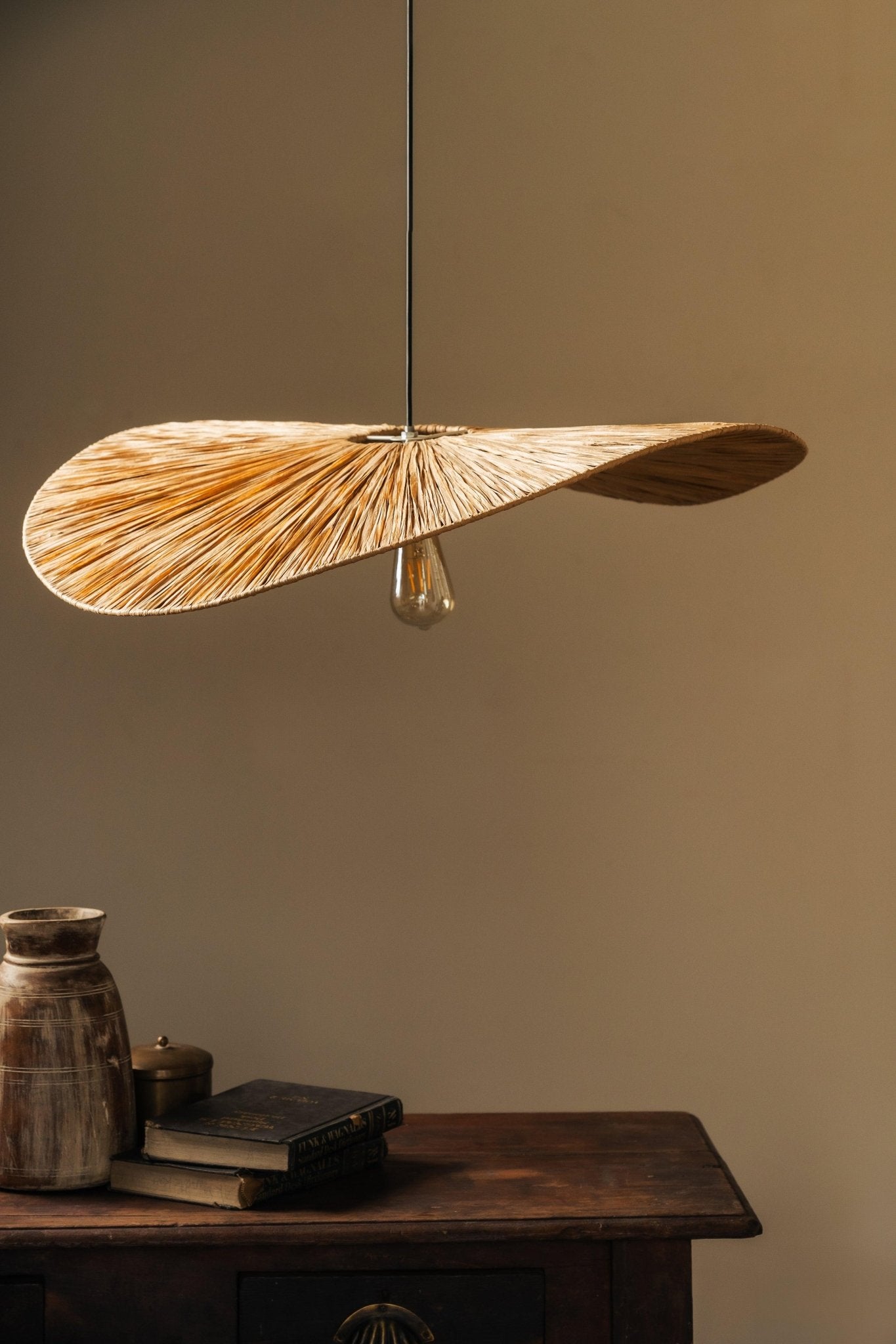 Decorative pendant light with natural material on a wooden table against a plain wall.