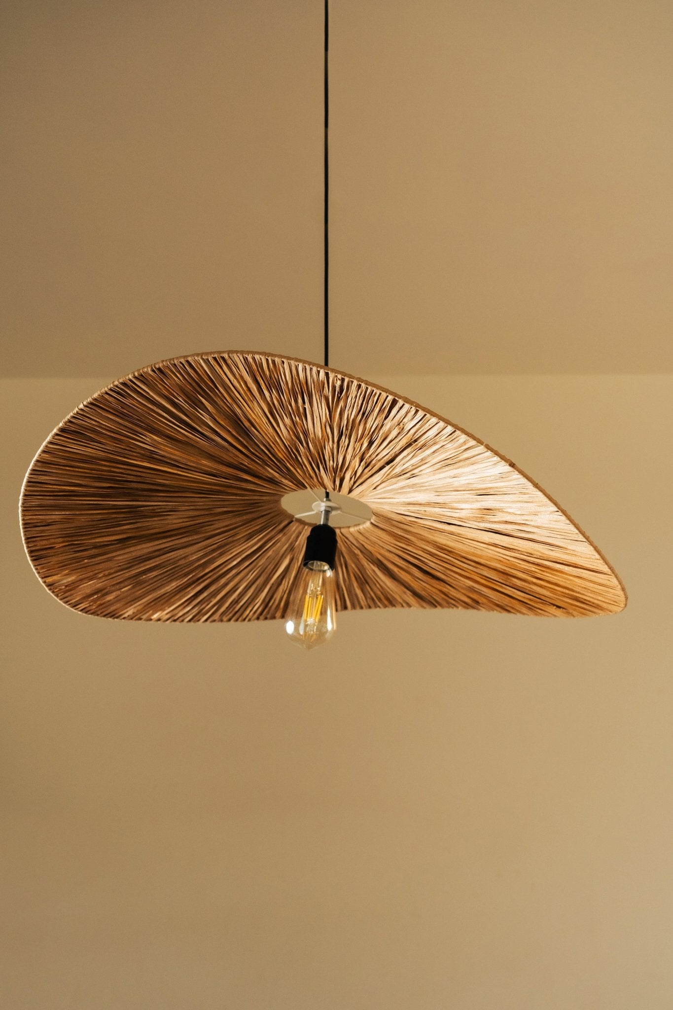 Wooden pendant light with a leaf-like design on a beige background