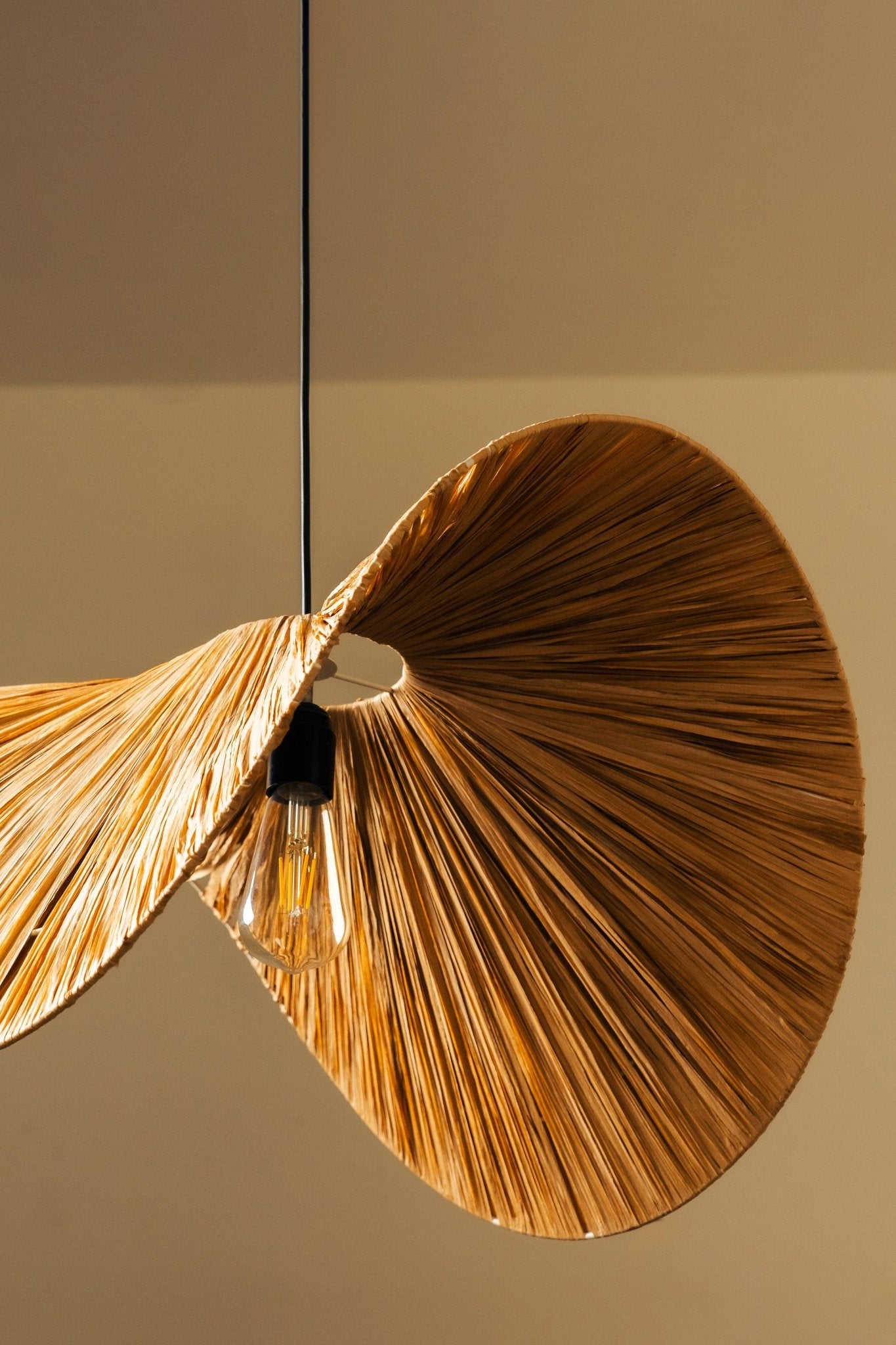 Decorative ceiling light fixture with gold leaf-like design on a neutral background