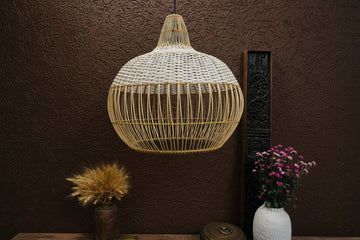 Woven pendant light hanging against a brown wall with decorative elements.