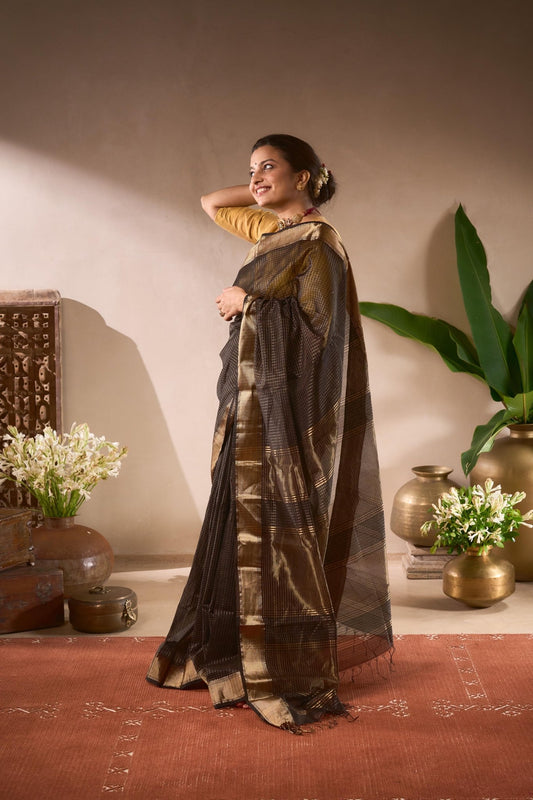 Woman in a traditional saree standing in a room with decorative elements.