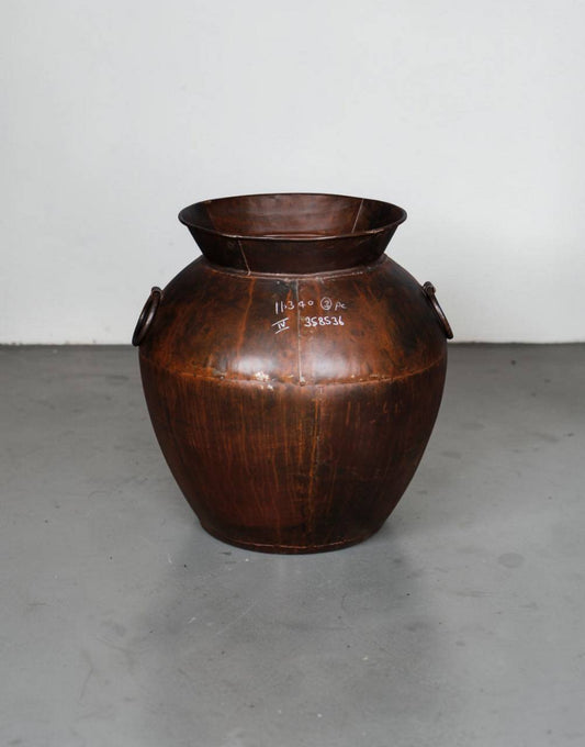 Brown leather container on a gray floor with a white wall background
