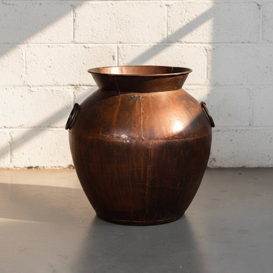 Brown leather container on a gray floor with a white wall background