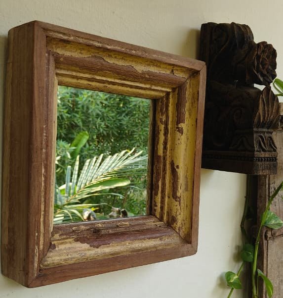 Wooden-framed mirror on a wall with a garden view
