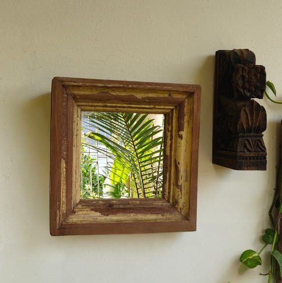 Wooden framed mirror on a wall with a view of greenery