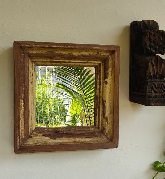 Wooden framed mirror on a wall with a view of greenery outside