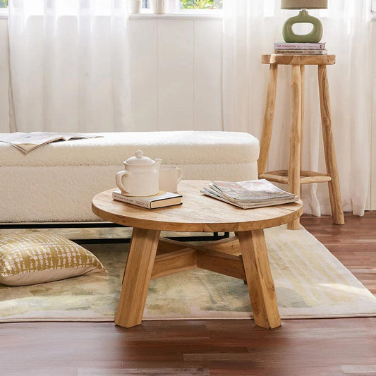 Wooden coffee table with a teacup and books in a living room setting.