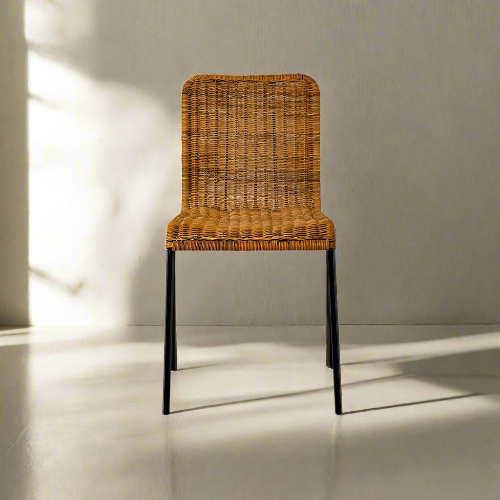 Wicker chair with black legs on a light gray floor and wall