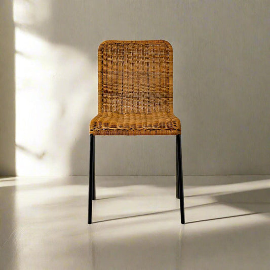 Wicker chair with black legs on a light gray floor and wall