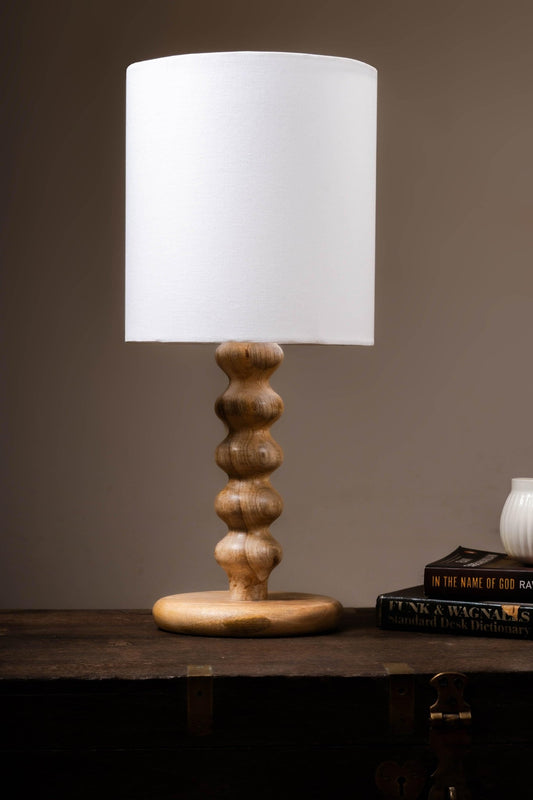 Artisan-carved wooden lamp base showcasing natural grain patterns and smooth sculptural contours