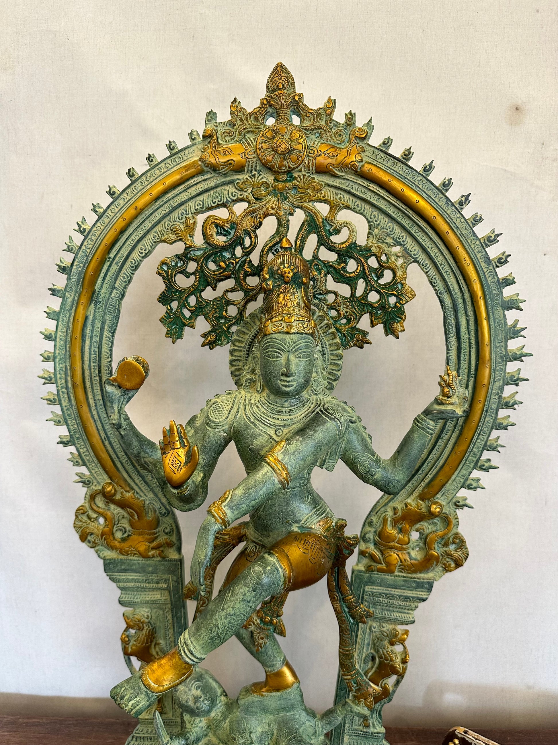 Bronze statue of a deity with intricate design on a plain background