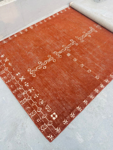 Brown rug with white patterns on a light gray floor