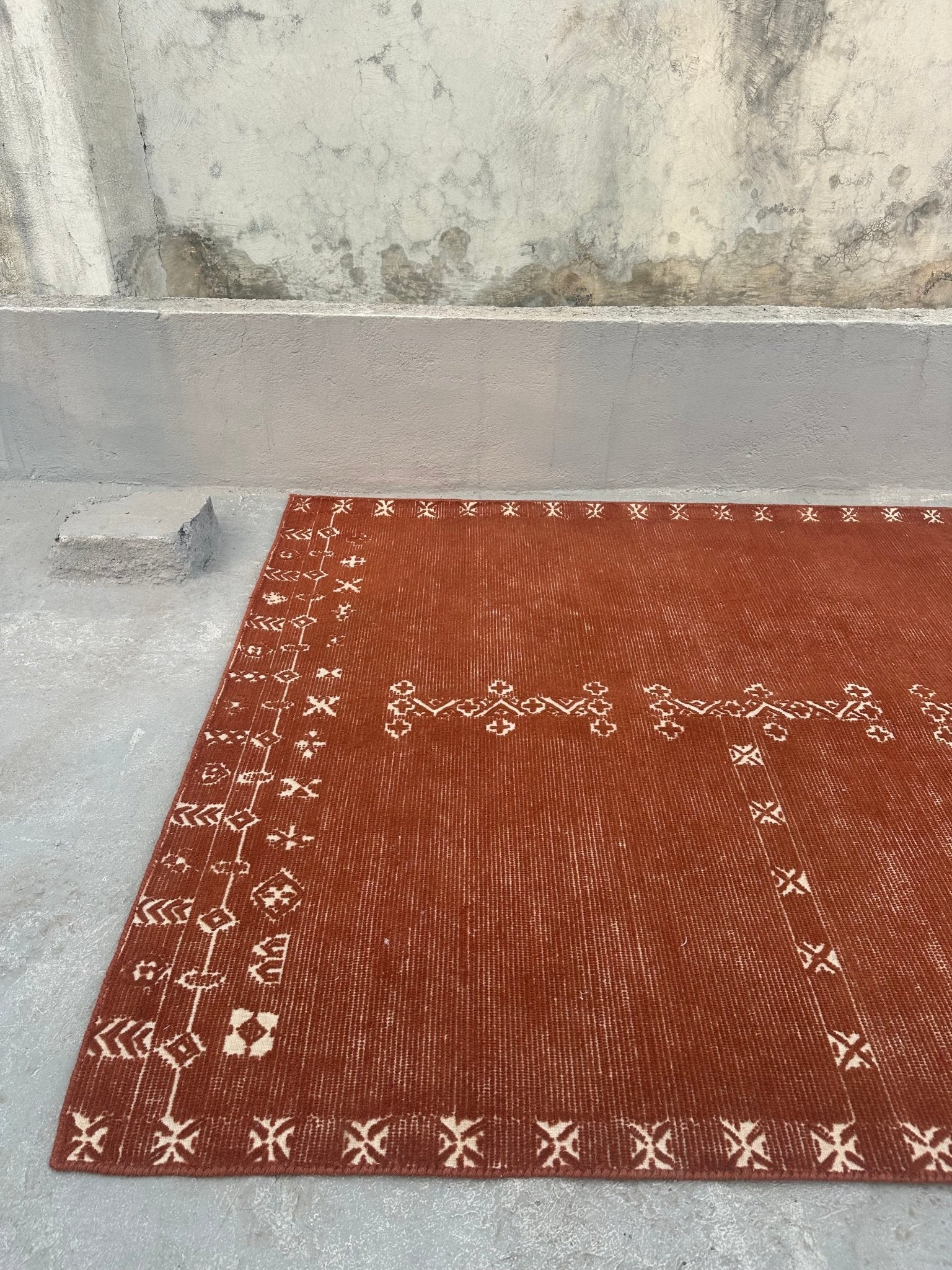 Brown rug with geometric patterns on a gray floor.