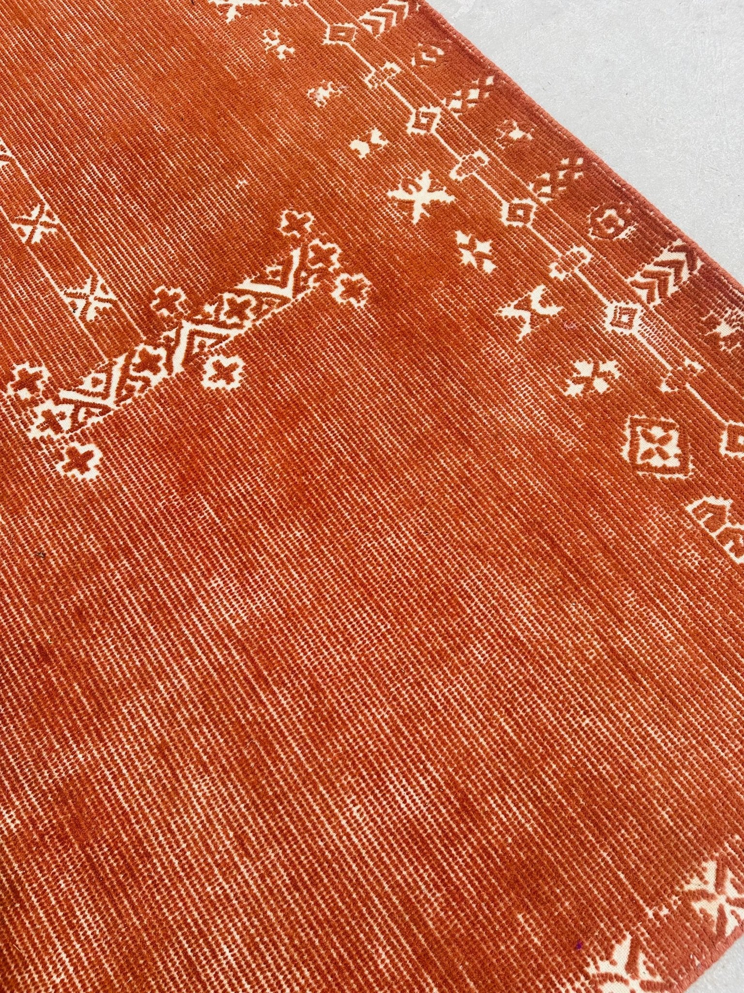 Close-up of a red patterned rug with white geometric designs.
