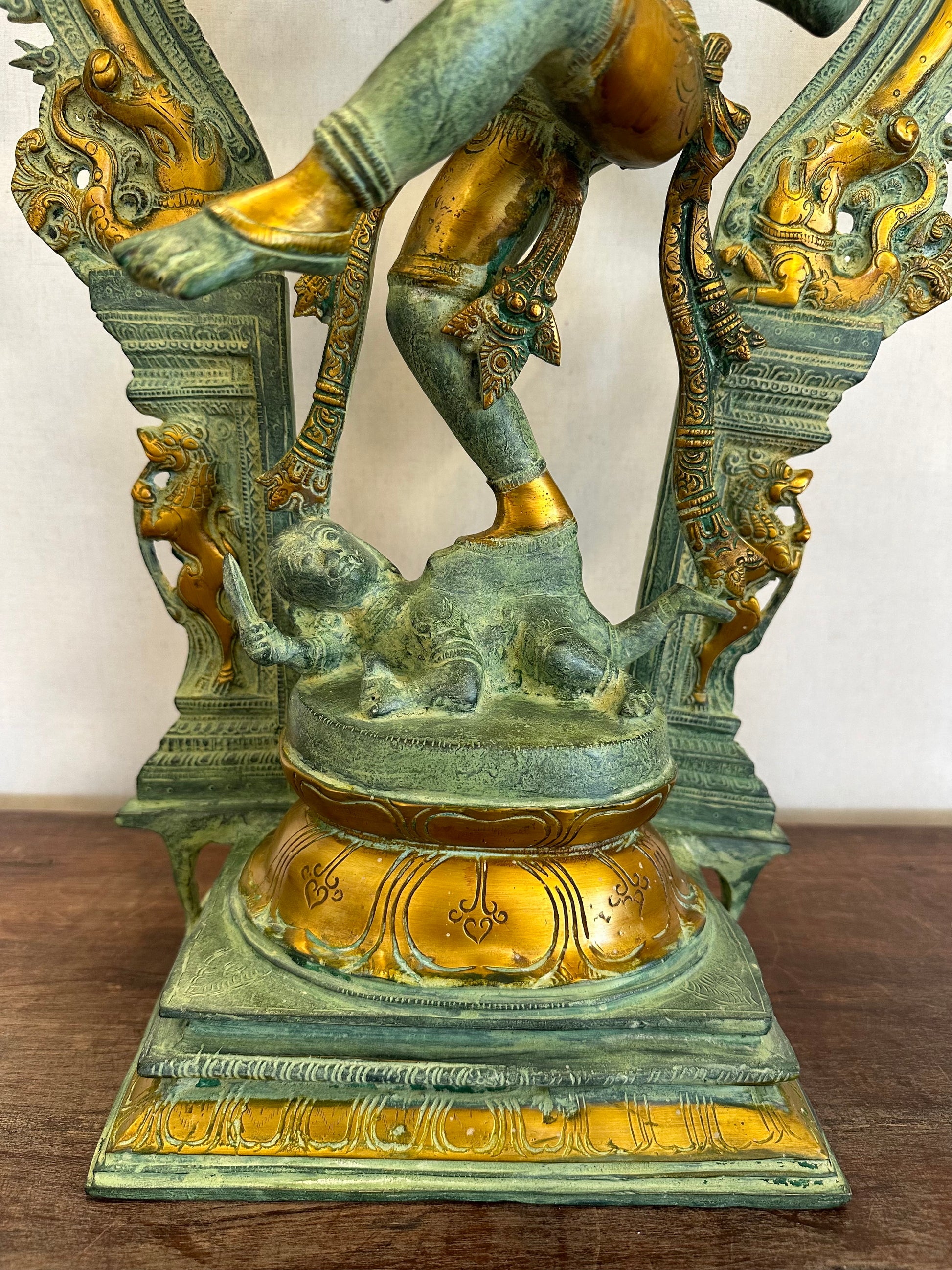 Decorative statue with gold and green finish on a wooden surface