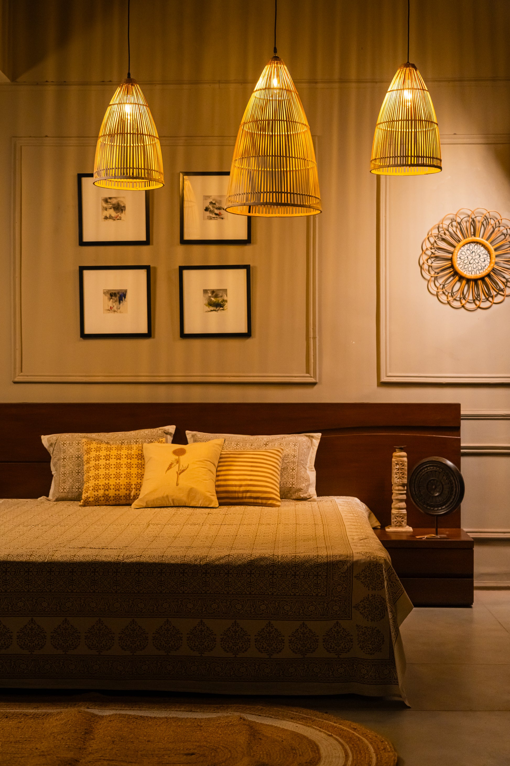 Decorative bedroom with a bed, pillows, and wall art illuminated by hanging lamps.