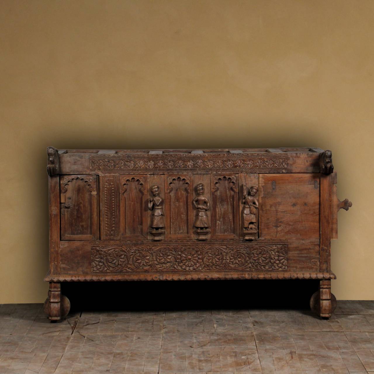 Carved wooden chest against a yellow wall