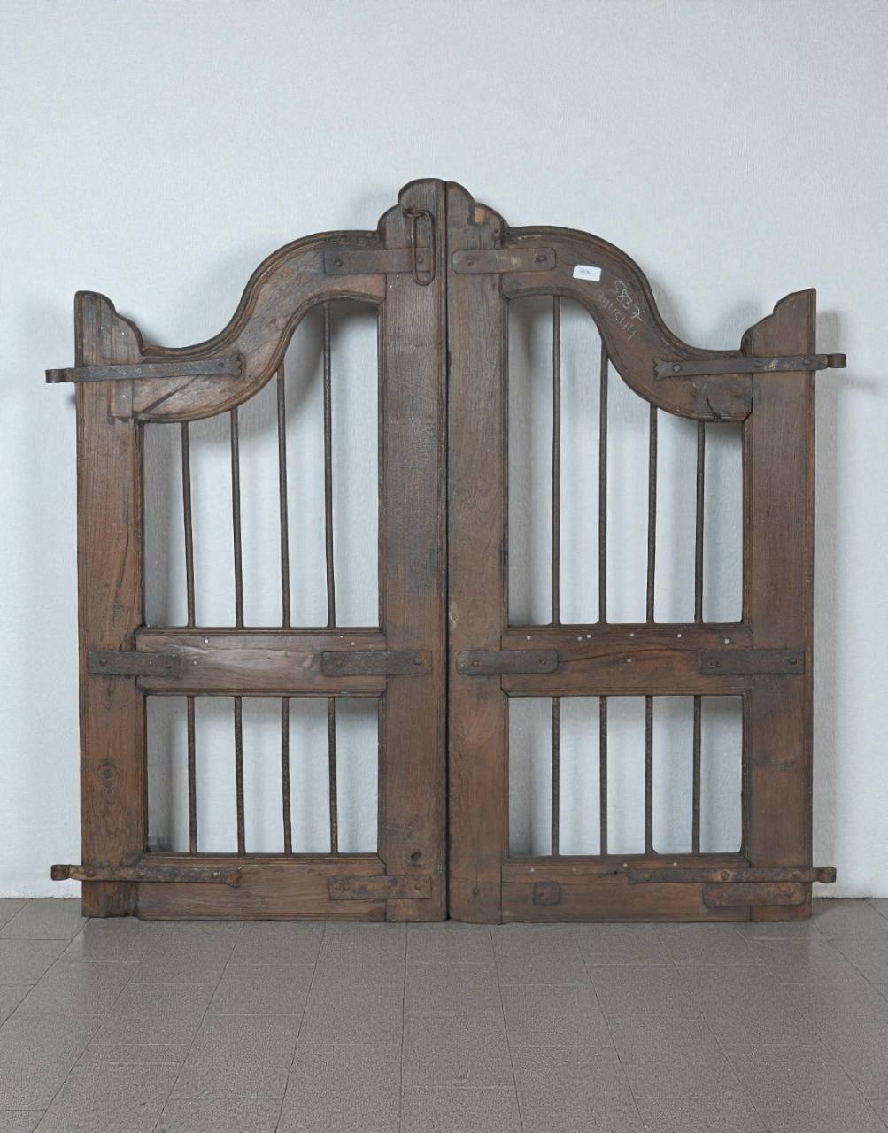 Pair of wooden gates with decorative top sections on a plain background
