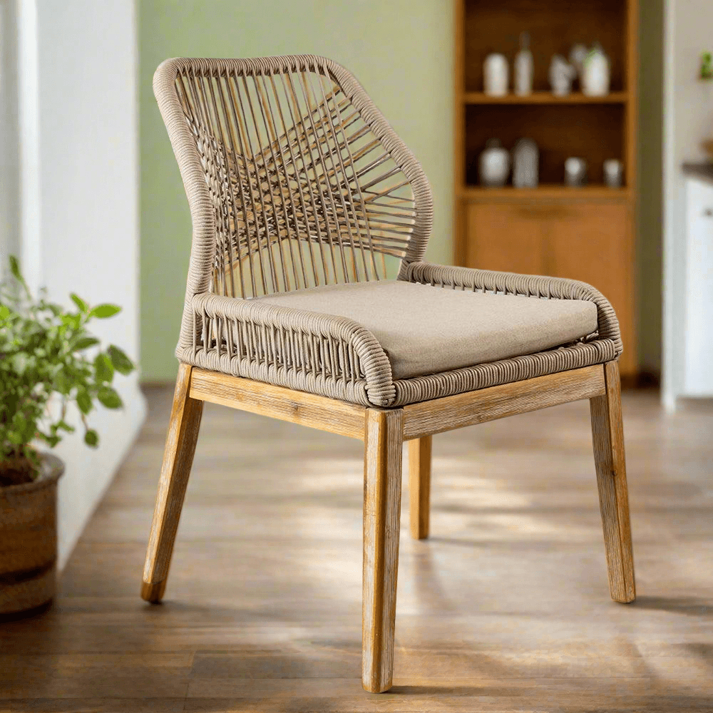 Wicker chair with cushion on a wooden floor in a room with a plant and shelves.