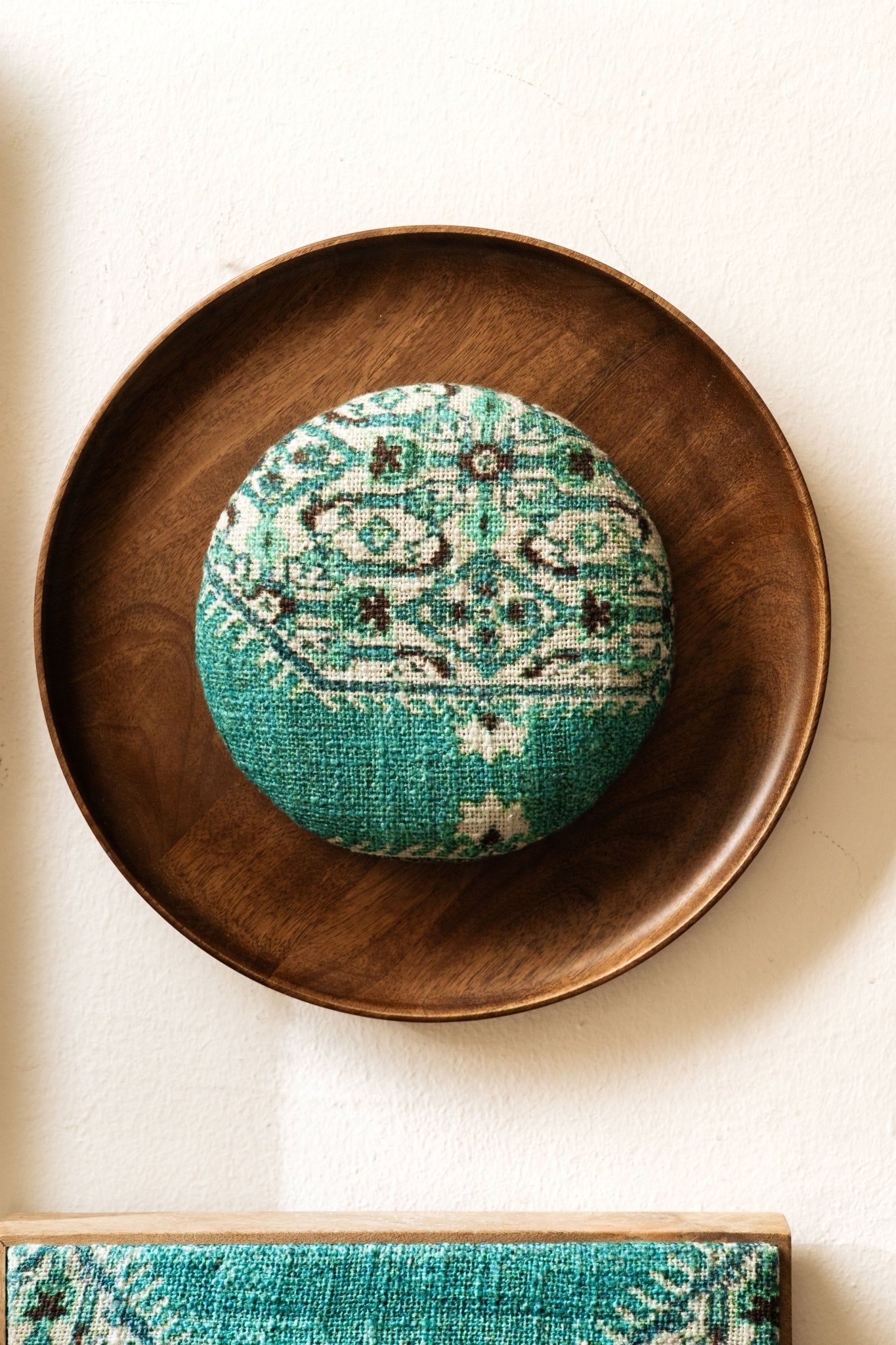 Turquoise decorative item on a wooden plate with a white background