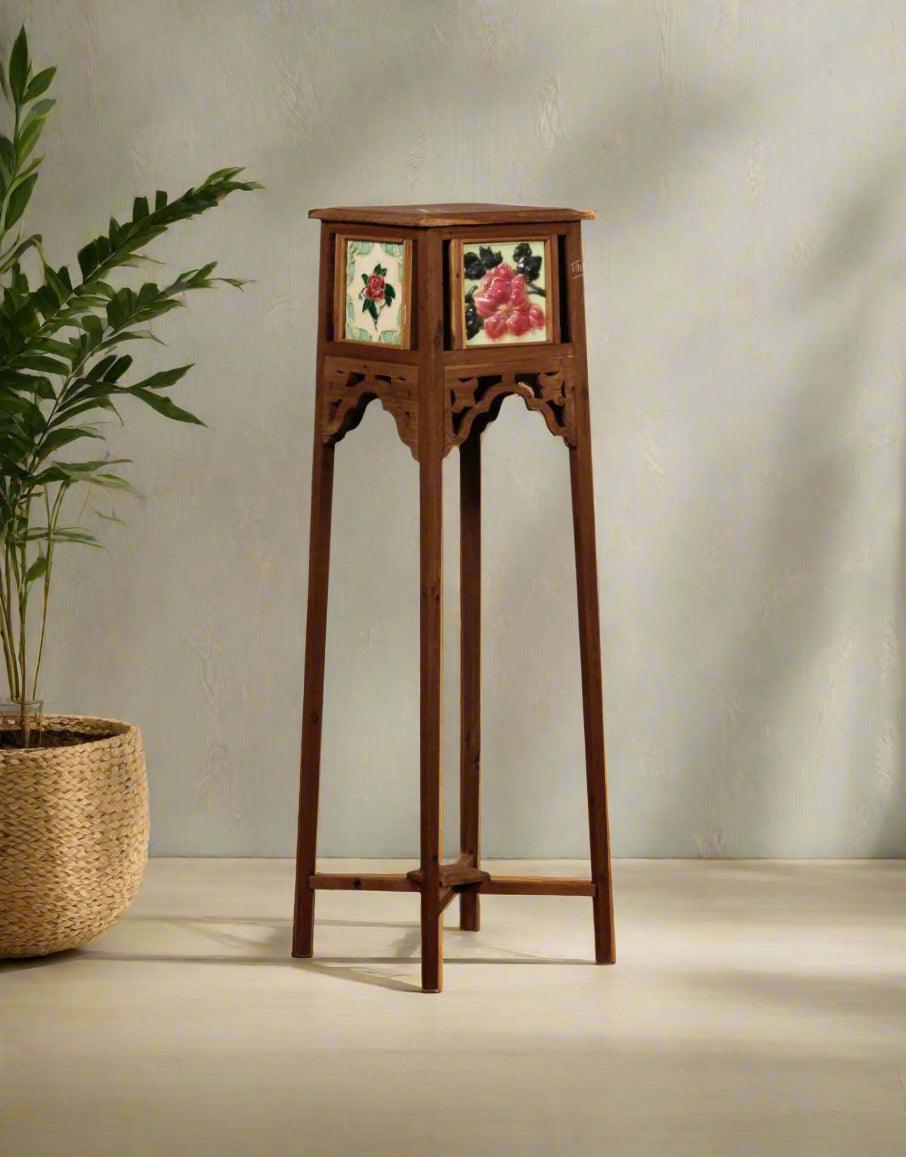Wooden plant stand with decorative panels against a plain wall