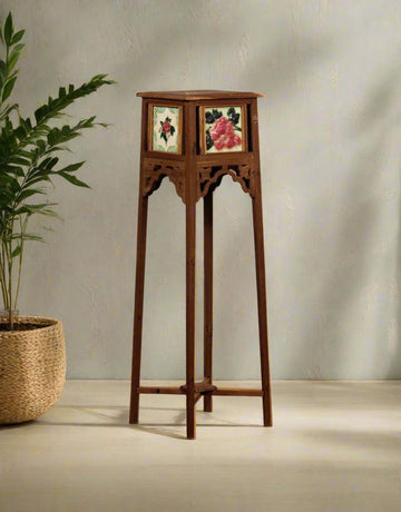 Wooden plant stand with decorative panels against a plain wall