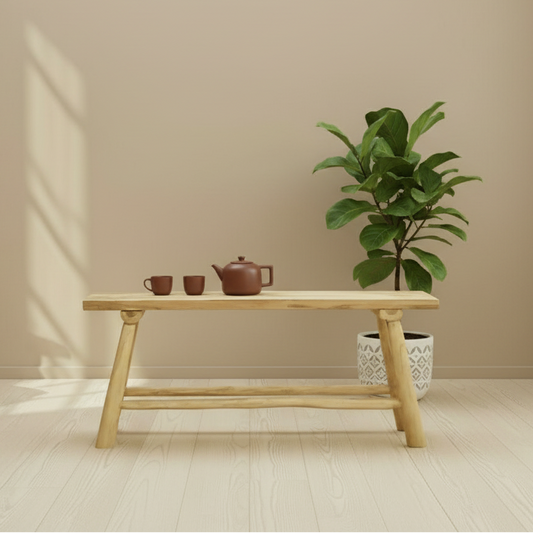 Wooden table with tea set and plant against a beige wall