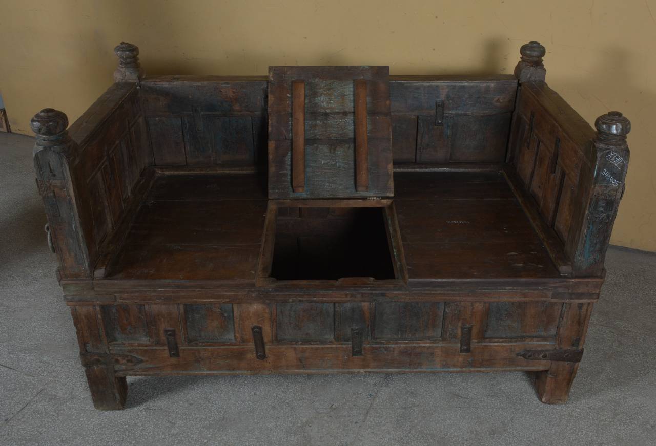 Vintage wooden bench with intricate carvings on a plain floor.