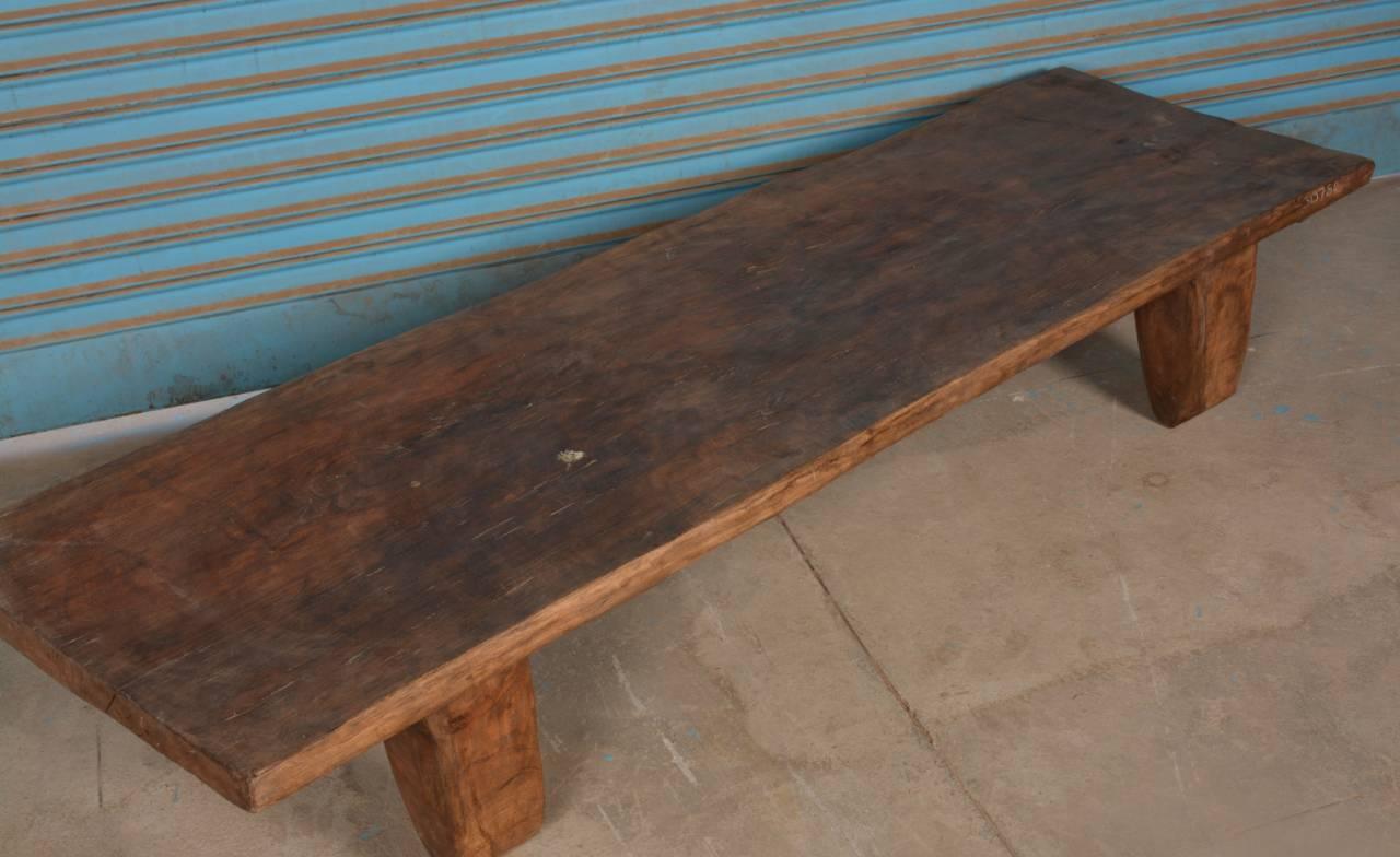 Long wooden bench against a blue striped wall.