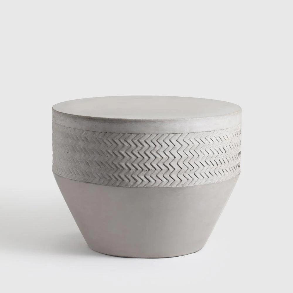 Concrete side table with textured design on a white background
