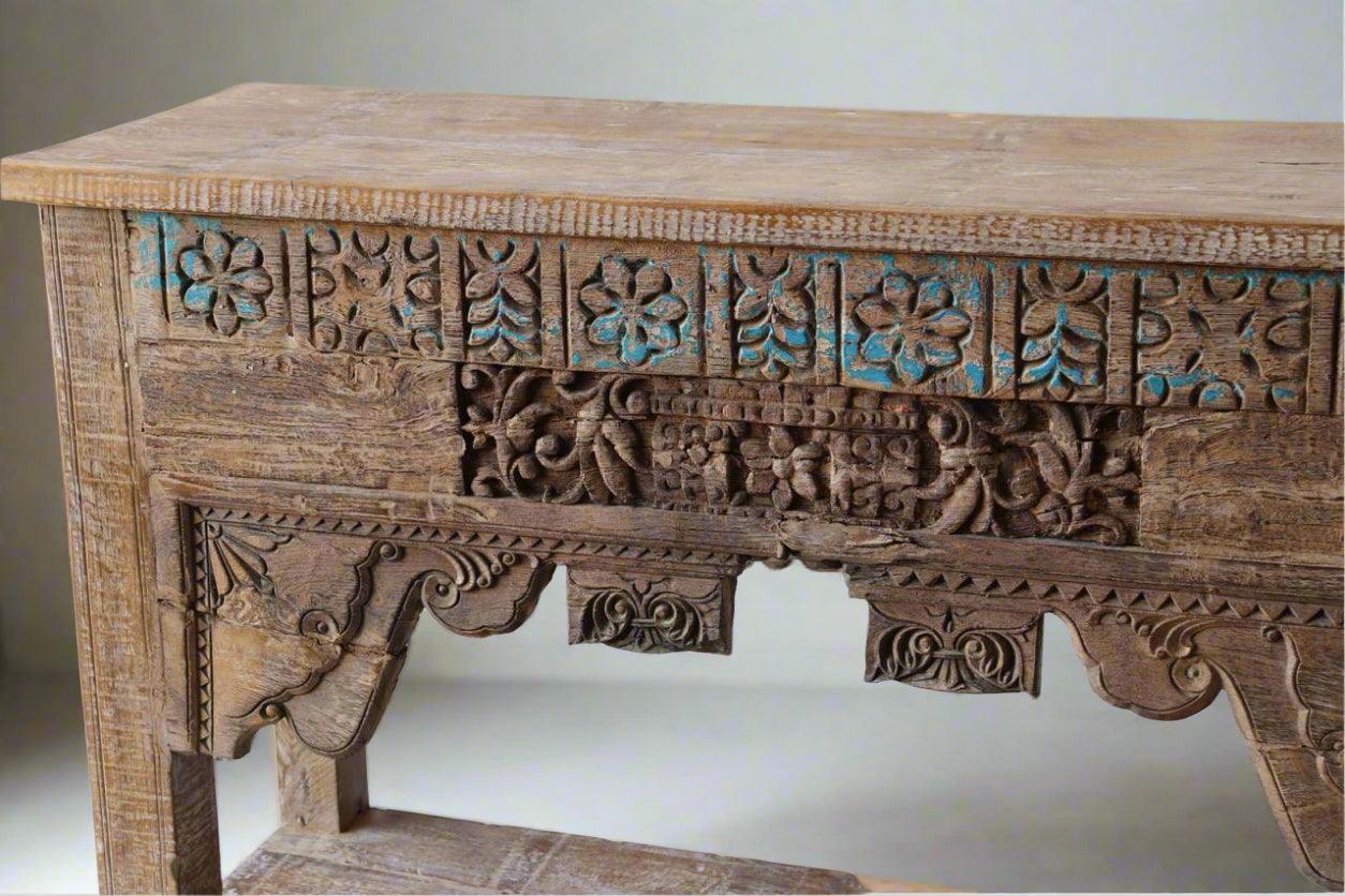 Wooden table with intricate carvings and turquoise accents on a plain background