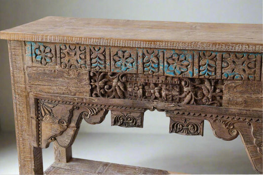 Wooden table with intricate carvings and turquoise accents on a plain background