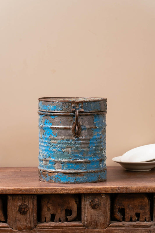 Close-up of vintage blue iron canister showing distressed patina and classic lid detail