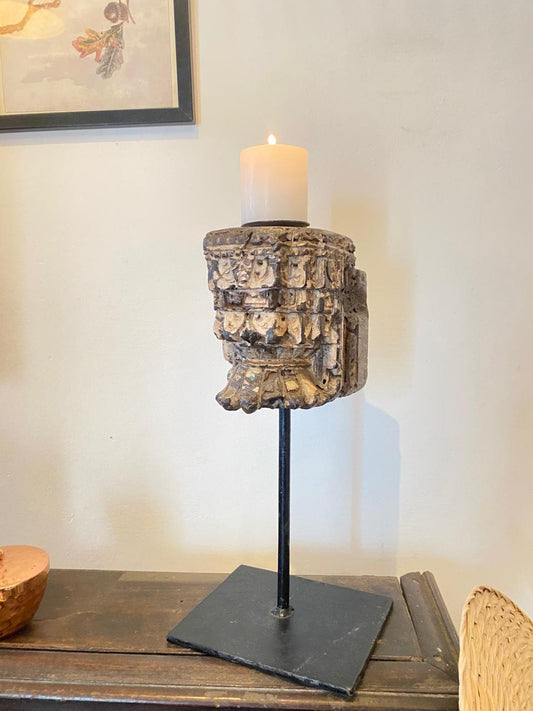 Decorative candle holder with textured design on a stand, placed on a wooden surface.