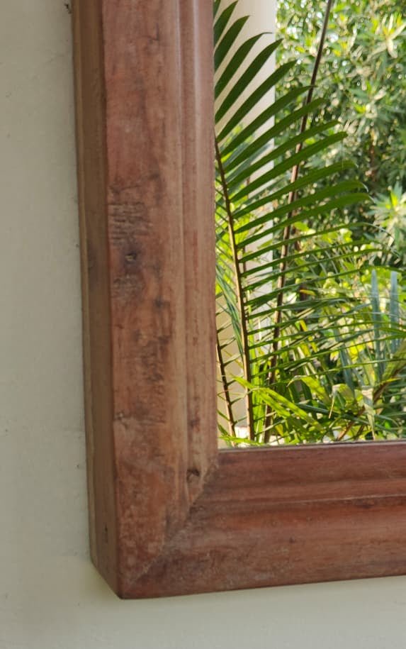 Wooden frame leaning against a wall with greenery in the background
