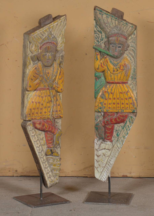 decorative panels with figurative designs on stands against a beige wall.