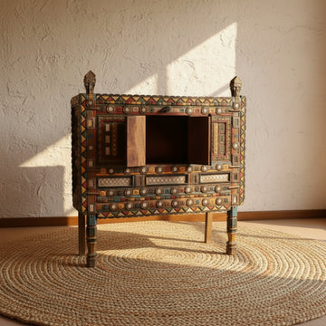 Decorative wooden cabinet with colorful inlay work on a striped background