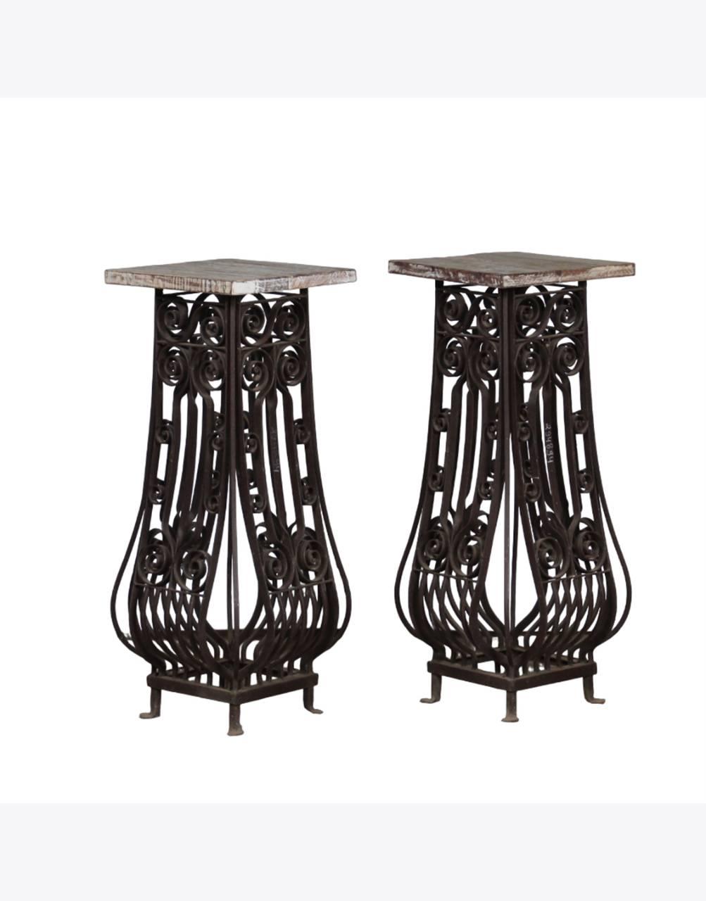 Two ornate metal stands with wooden tops on a white background
