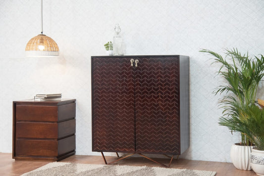 Wooden cabinet with chevron pattern in a room with a lamp, plant, and small table.