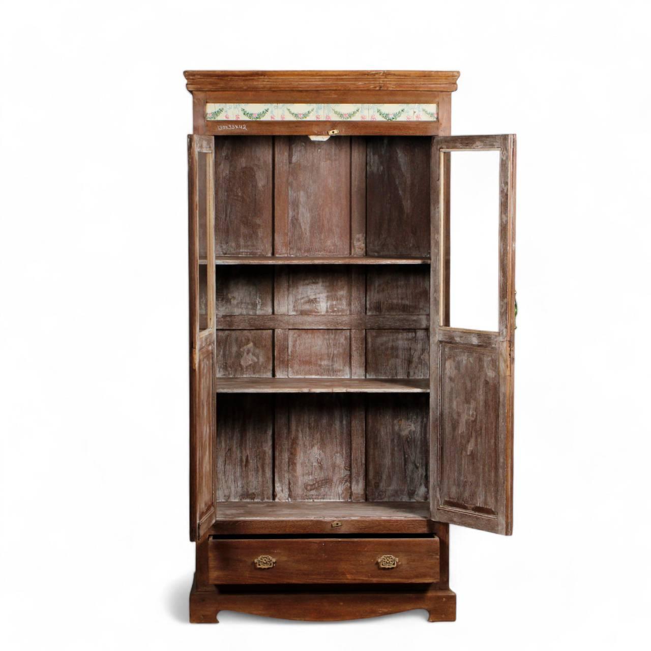 Close-up of wooden glass almirah showing intricate floral carvings and traditional Indian craftsmanship on teak wood