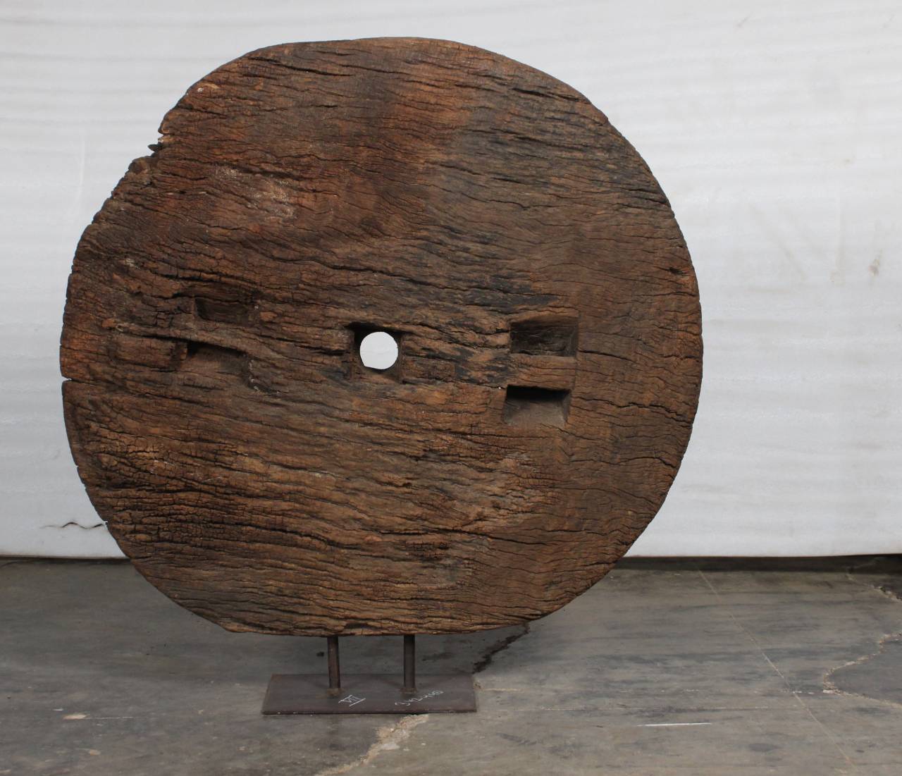 Large wooden spool on a stand against a white wall