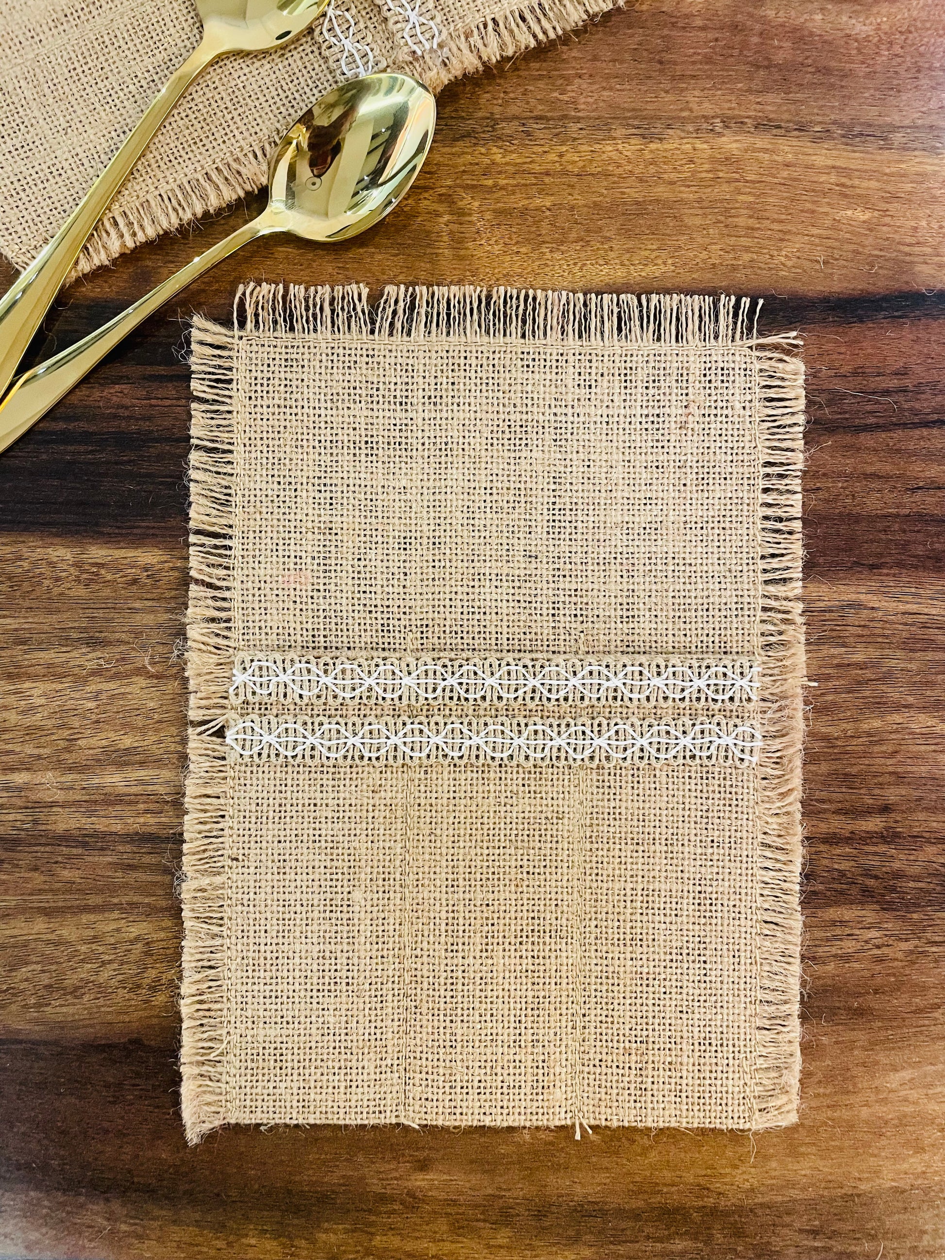 A set of cutlery holder made from natural jute and embellished with beautiful laces will surely add charm to your dining experience. It has three pockets perfectly sized to put small and big sized spoons , forks and knifes. Its neutral colour makes it perfect to go with both white and coloured crockery.