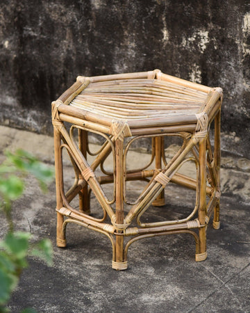 Hexagonal rattan stool against a textured wall