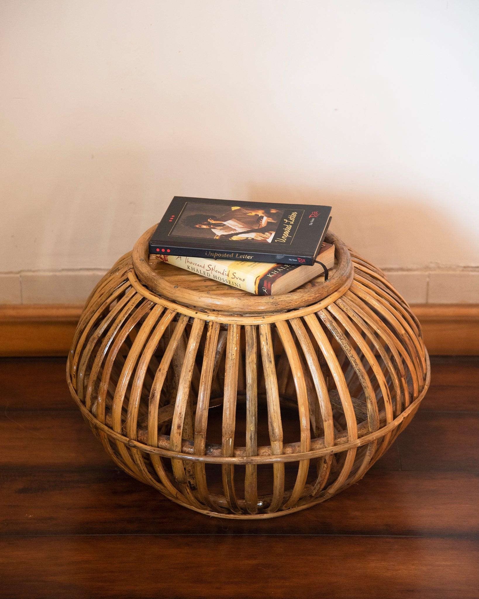 Wicker side table with books on a wooden floor